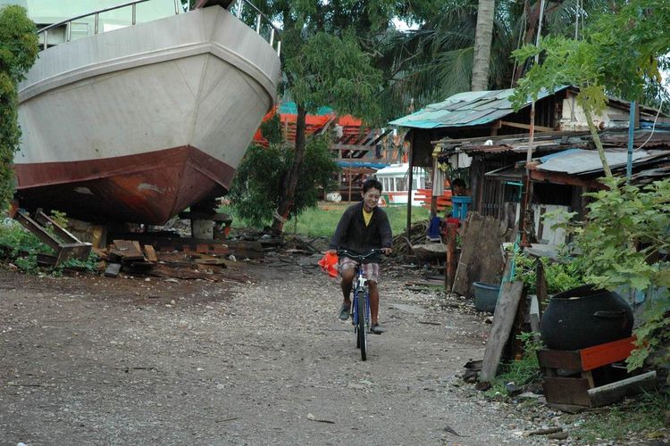 Burmese bicyclist at a boat yard.