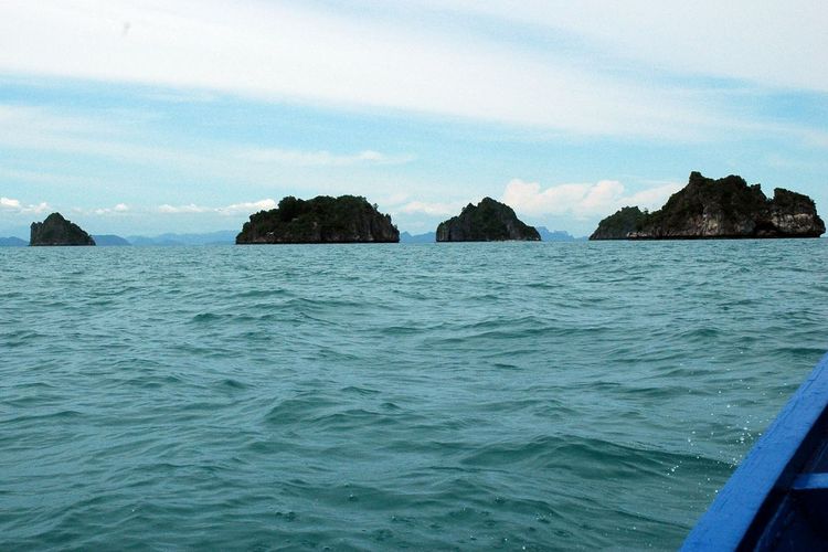 Off the bow of the long tail boat are four of the Five Islands.