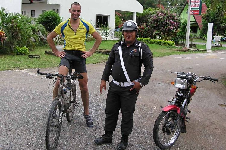 This friendly Lang Suan motorcycle policeman escorts a muddy Simon to the motel.